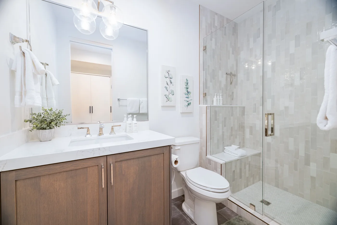 A bright bathroom with a wide vanity, sink, and glass-enclosed shower.