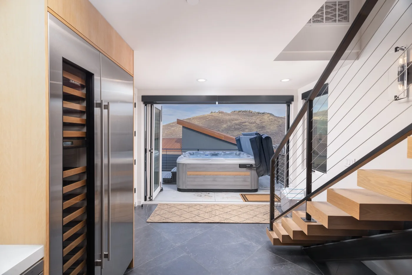 A modern interior opens onto a patio with a hot tub and a staircase.