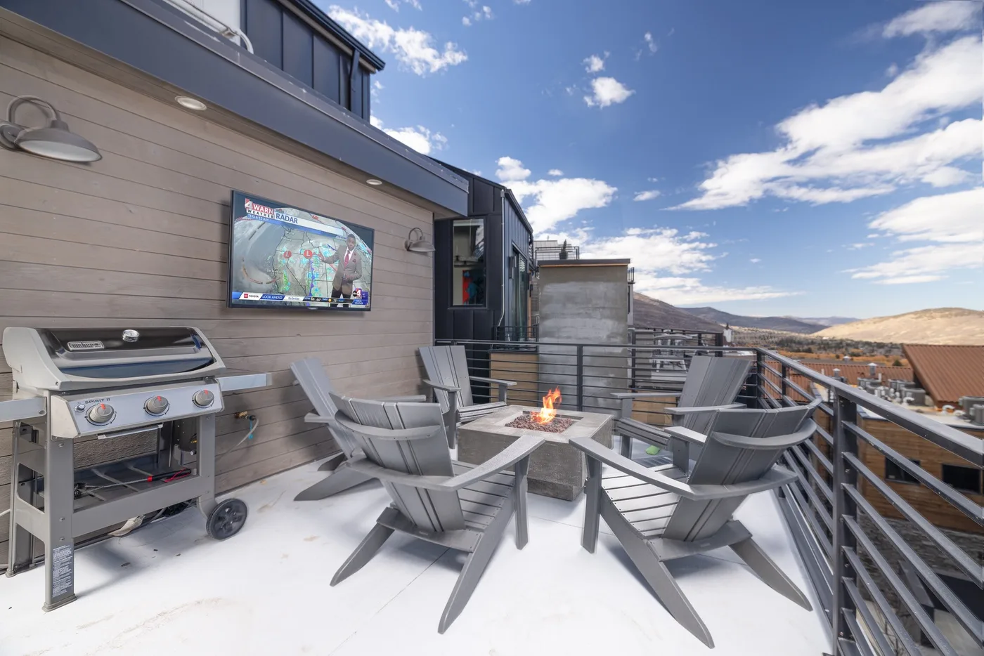 A rooftop terrace with outdoor seating, a grill, and a small fire table.