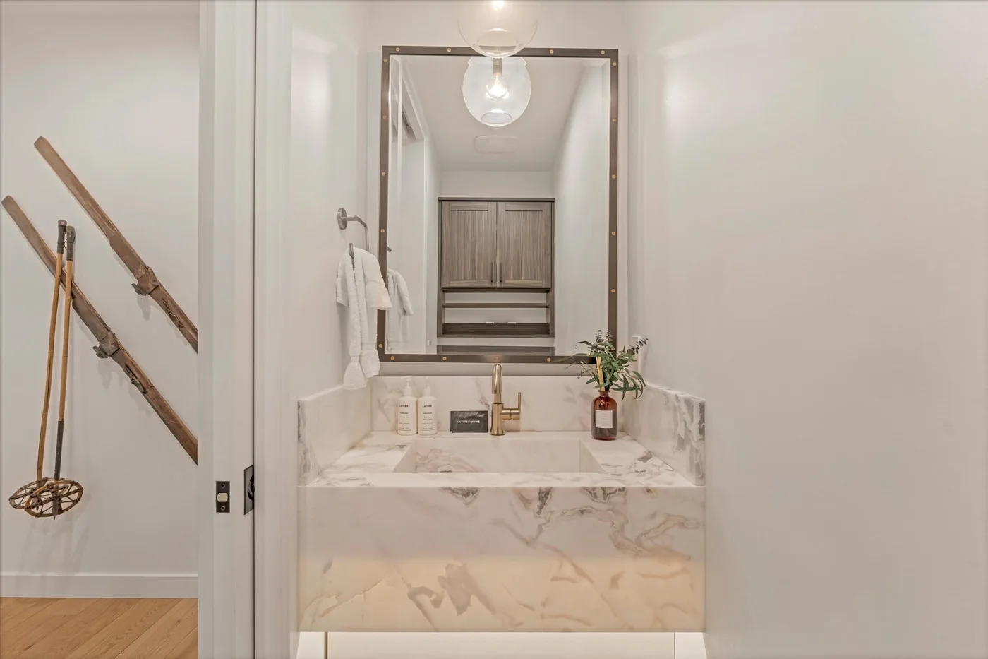 A bright bathroom vanity with a large mirror and marble-patterned counter.
