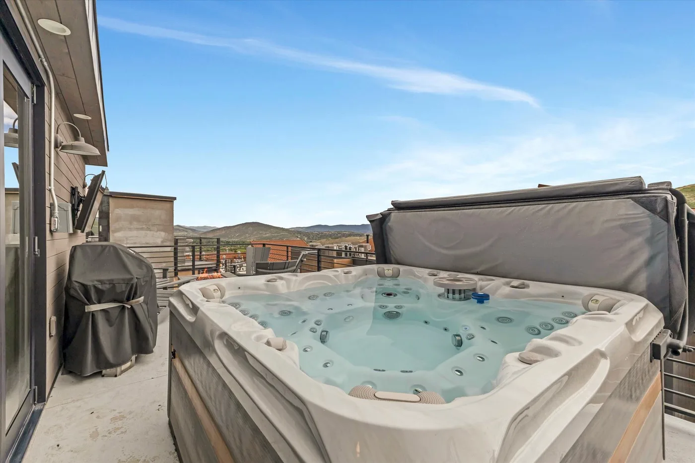 Outdoor hot tub on a rooftop terrace, with open sky and distant hills.