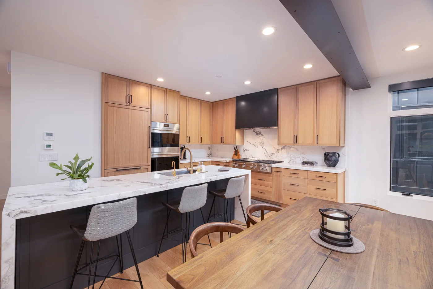 A modern kitchen with a marble island and wooden cabinets.