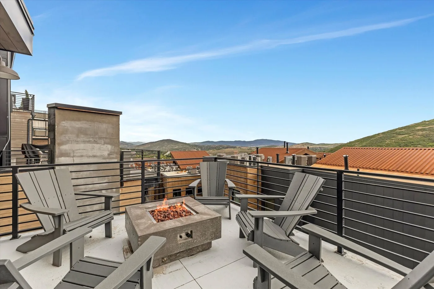 A rooftop terrace with outdoor seating and a fire pit overlooks the surrounding hills.