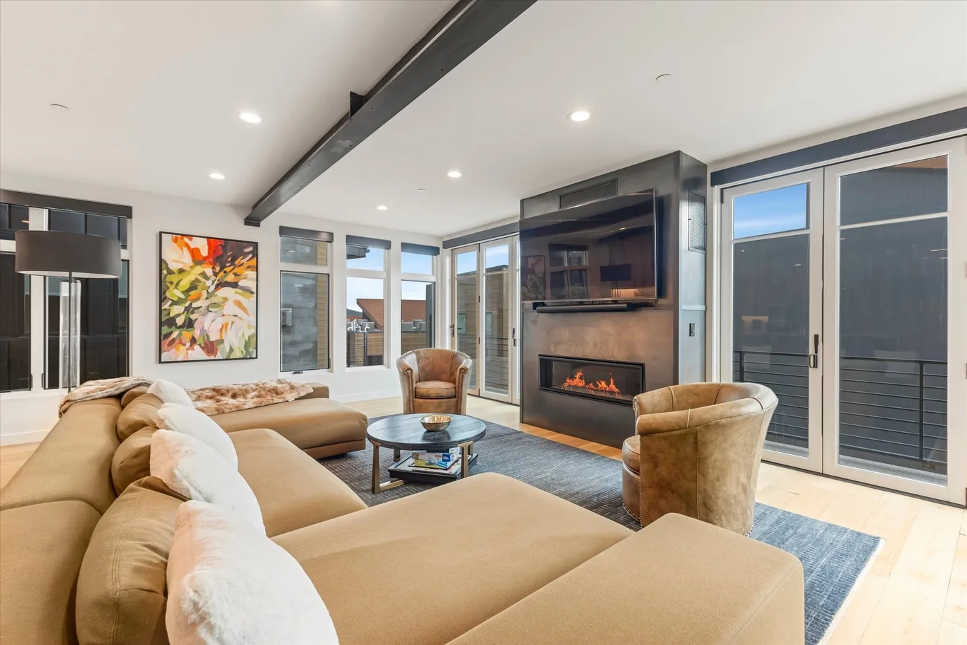 A bright living room with a sectional seating area and a fireplace beneath a television.