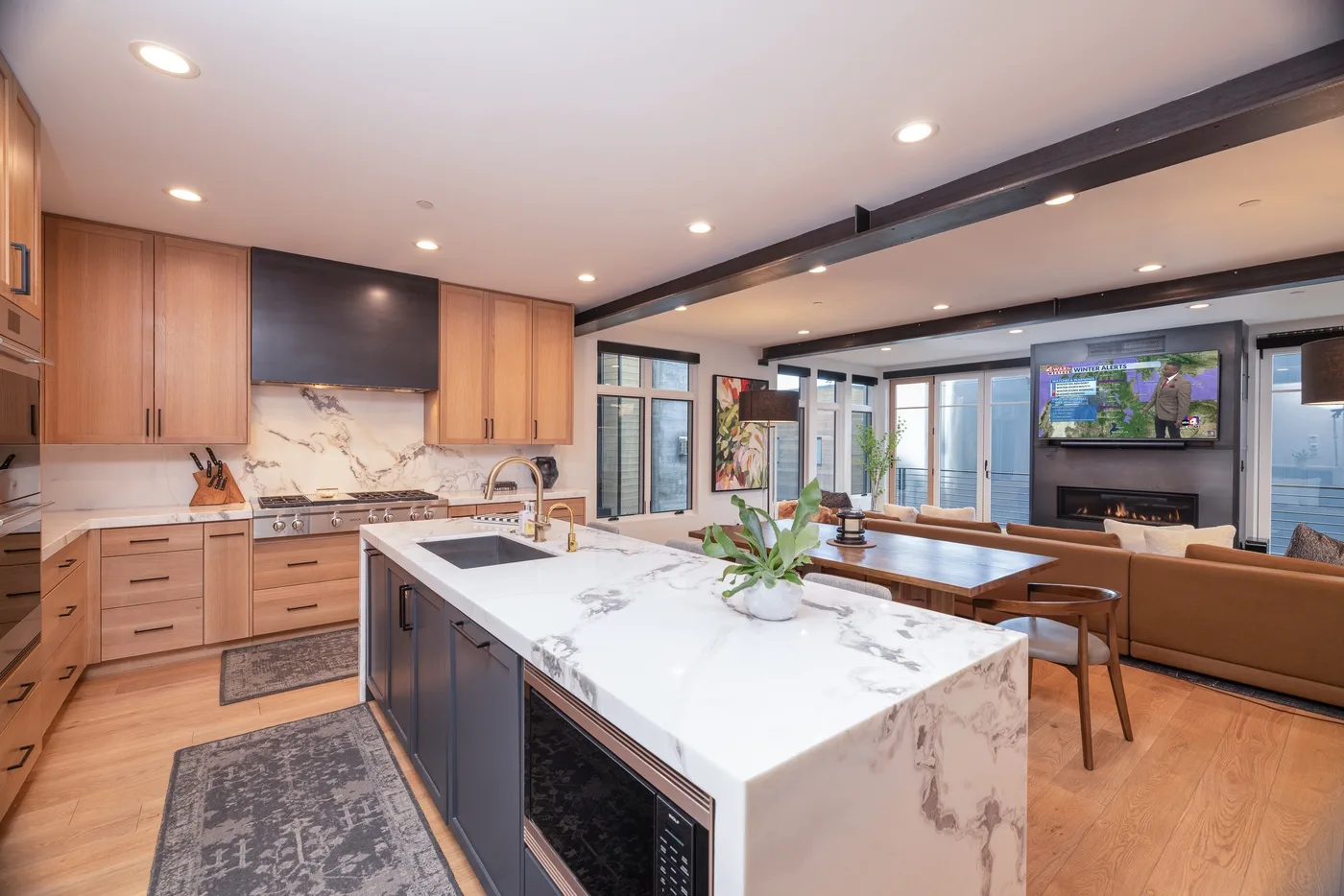 An open kitchen and dining area features a large island and a long wooden table.
