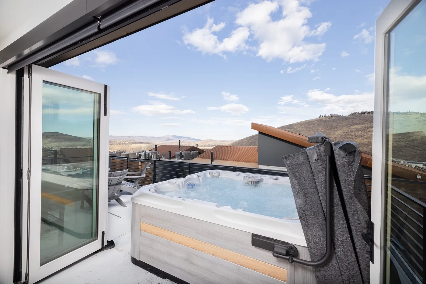An outdoor hot tub sits on a terrace overlooking distant hills.