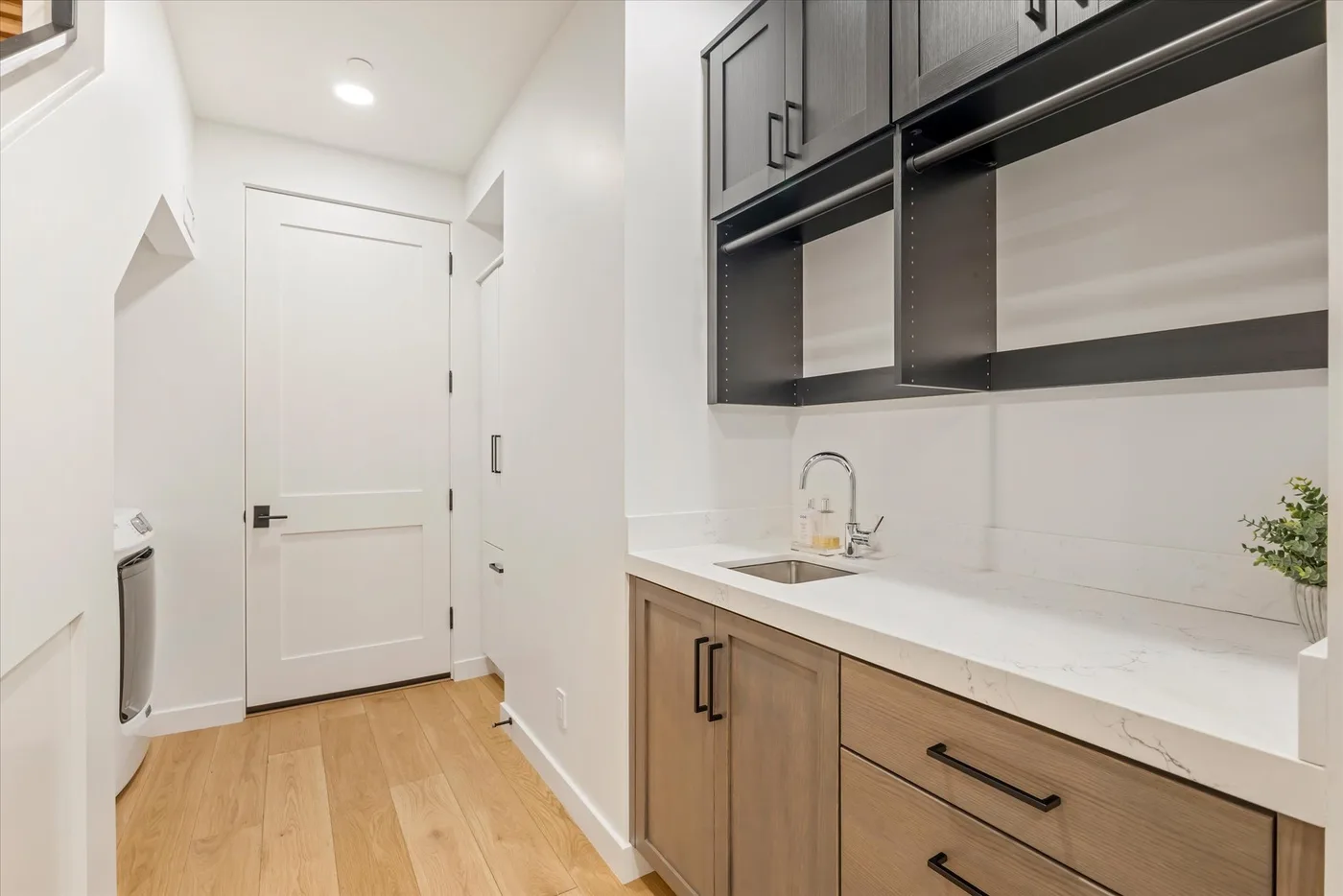 A bright laundry room with a counter, sink, and built-in cabinets.