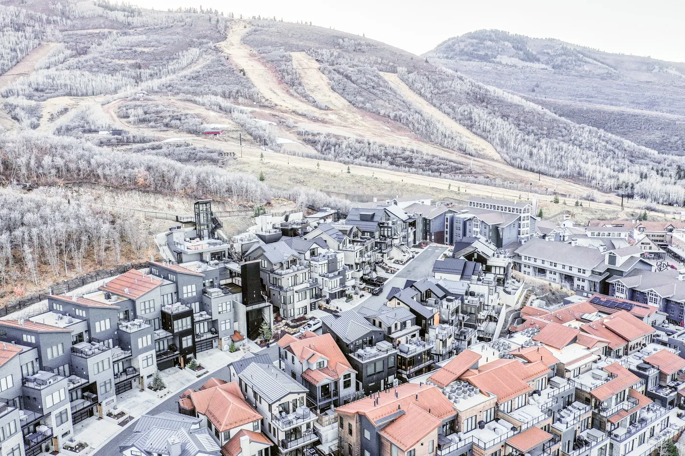 A mountain resort village sits below snow-covered ski slopes.