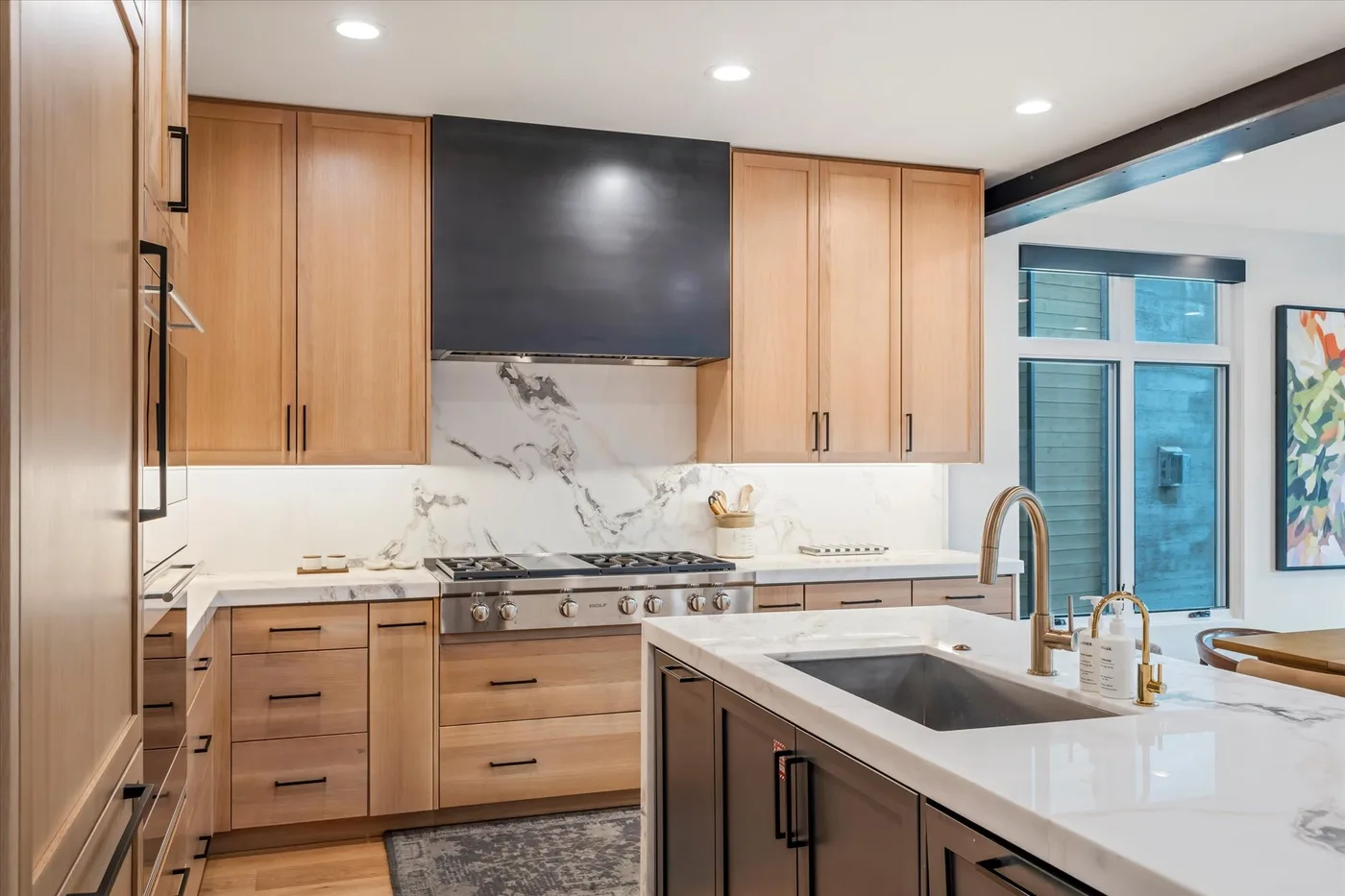 A modern kitchen with wooden cabinets, a large island, and stainless steel appliances.