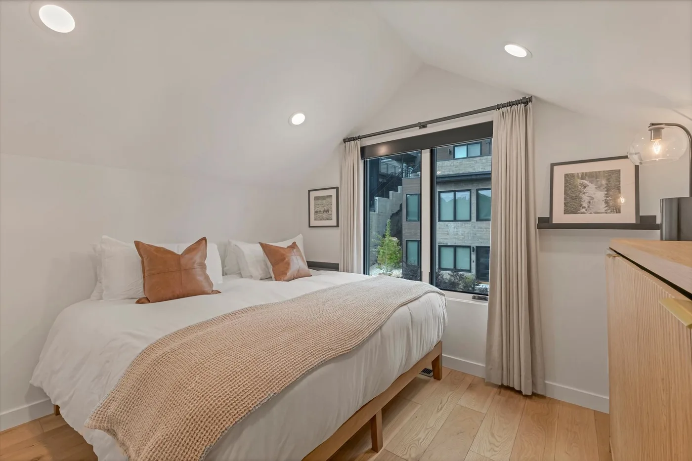 A bedroom with a neatly made bed beside a large window.