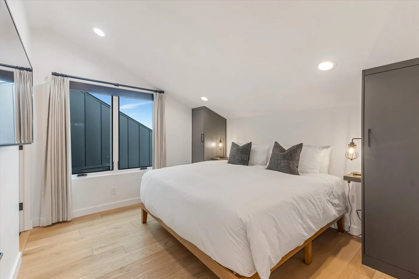 A bright bedroom with a large bed beside a window.