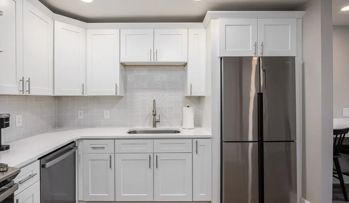 Una cocina luminosa con gabinetes blancos, un fregadero y electrodomésticos de acero inoxidable.