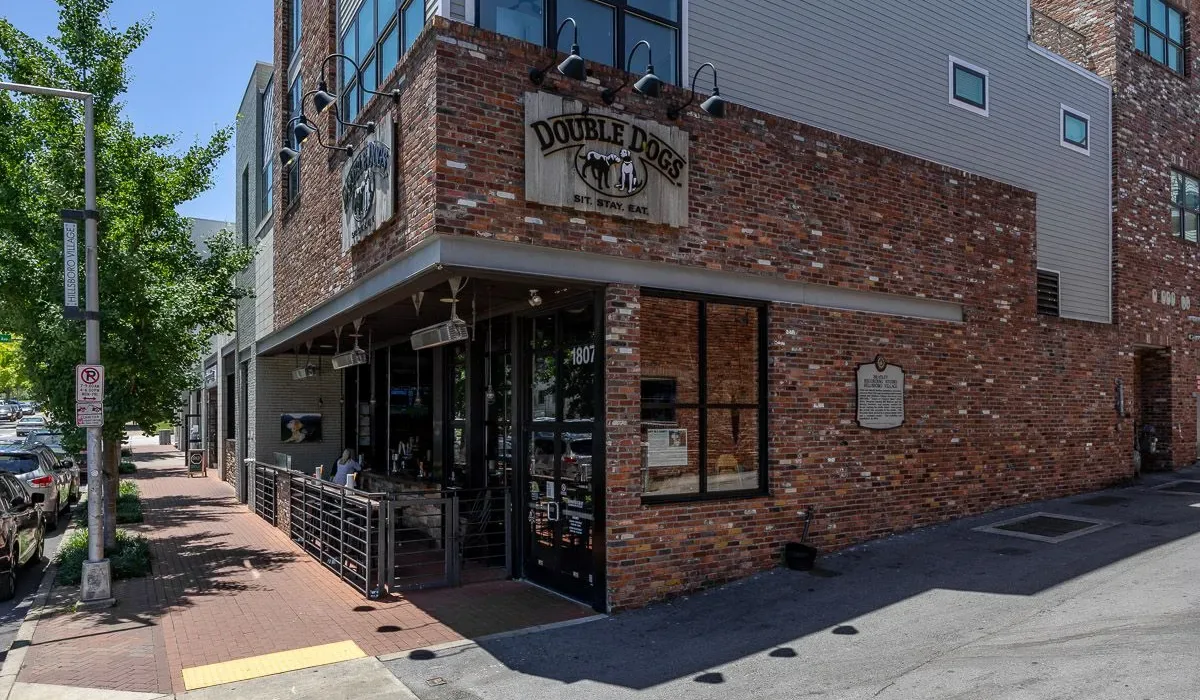 Un edificio comercial de ladrillo está junto a una acera, con una entrada de tienda sombreada.