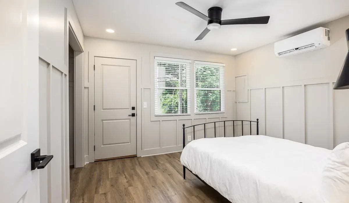 Un dormitorio con una cama, paredes con paneles y un ventilador de techo.