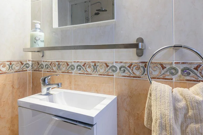 Un lavabo de baño está debajo de un espejo, con una toalla colgada al lado.