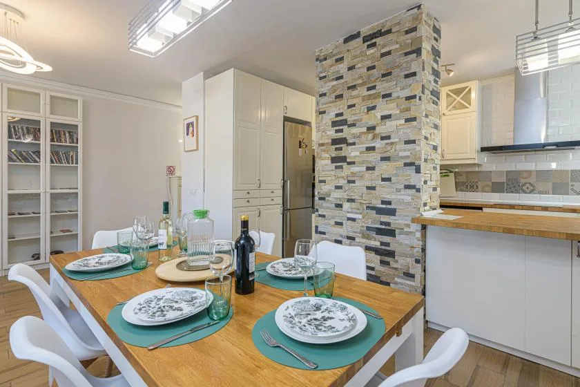 Una mesa de comedor puesta está junto a una cocina luminosa.
