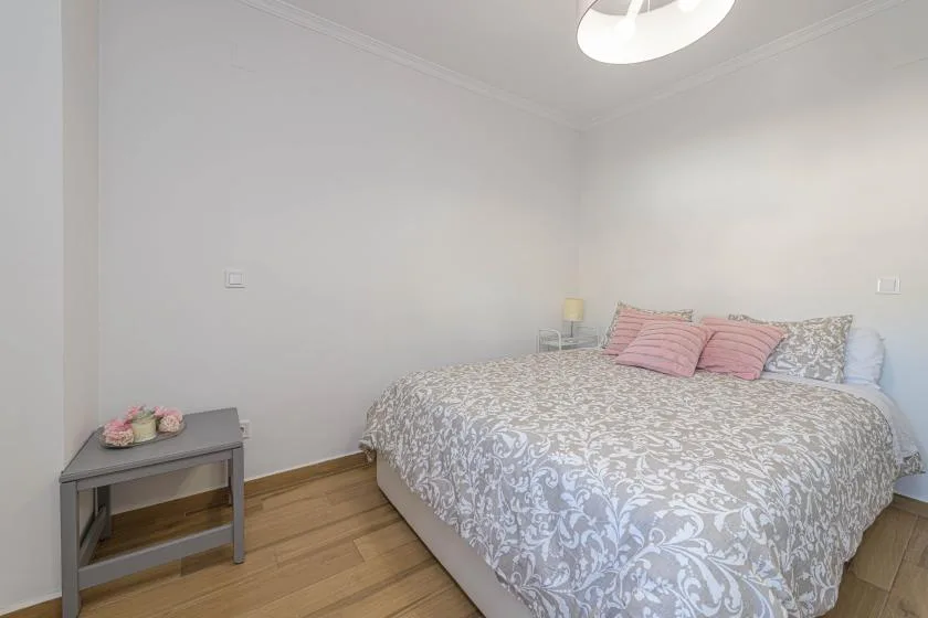 Un dormitorio con una cama cubierta con ropa de cama estampada y una mesita auxiliar.