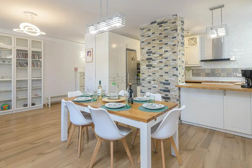 Comedor con la mesa puesta junto a una cocina abierta.