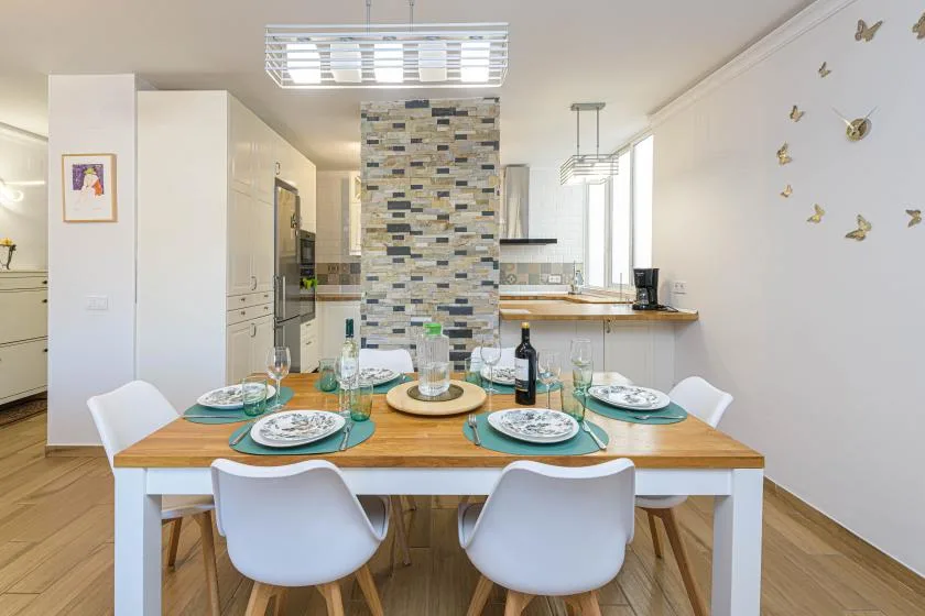 Una mesa de comedor preparada para comer está en una cocina abierta.