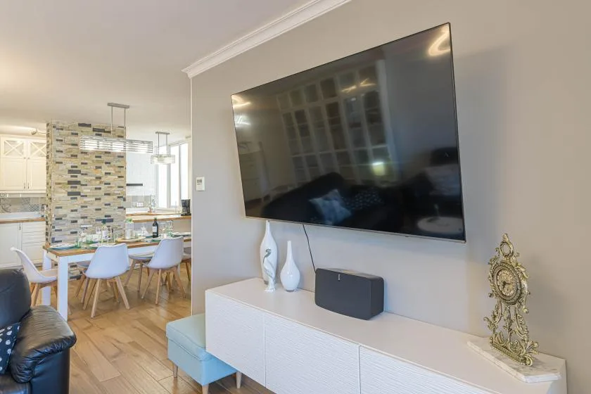 Una sala de estar con un televisor montado en la pared sobre un mueble blanco.