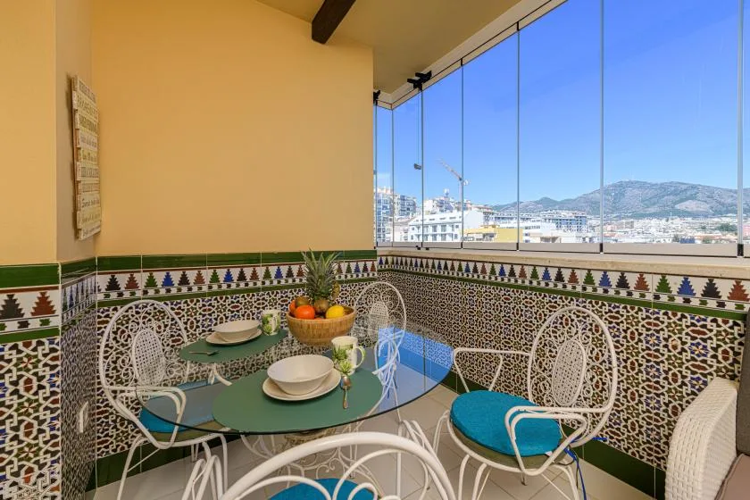 A sunroom dining area with a round table beside large windows overlooking the hills.