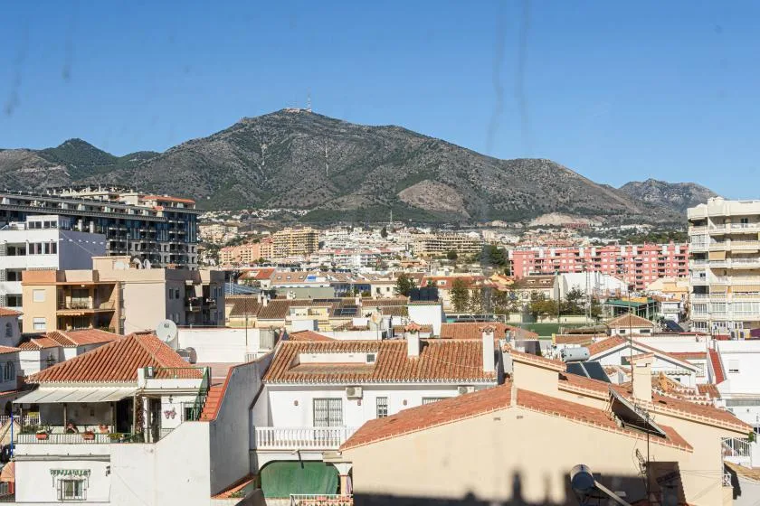 Una vista urbana de edificios muy juntos con una montaña al fondo.
