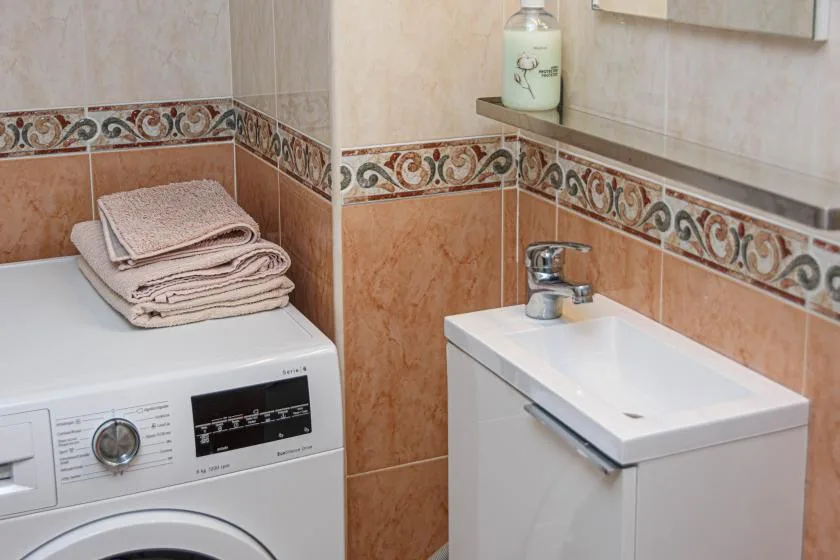 Zona de lavandería con una lavadora junto a un lavabo pequeño.