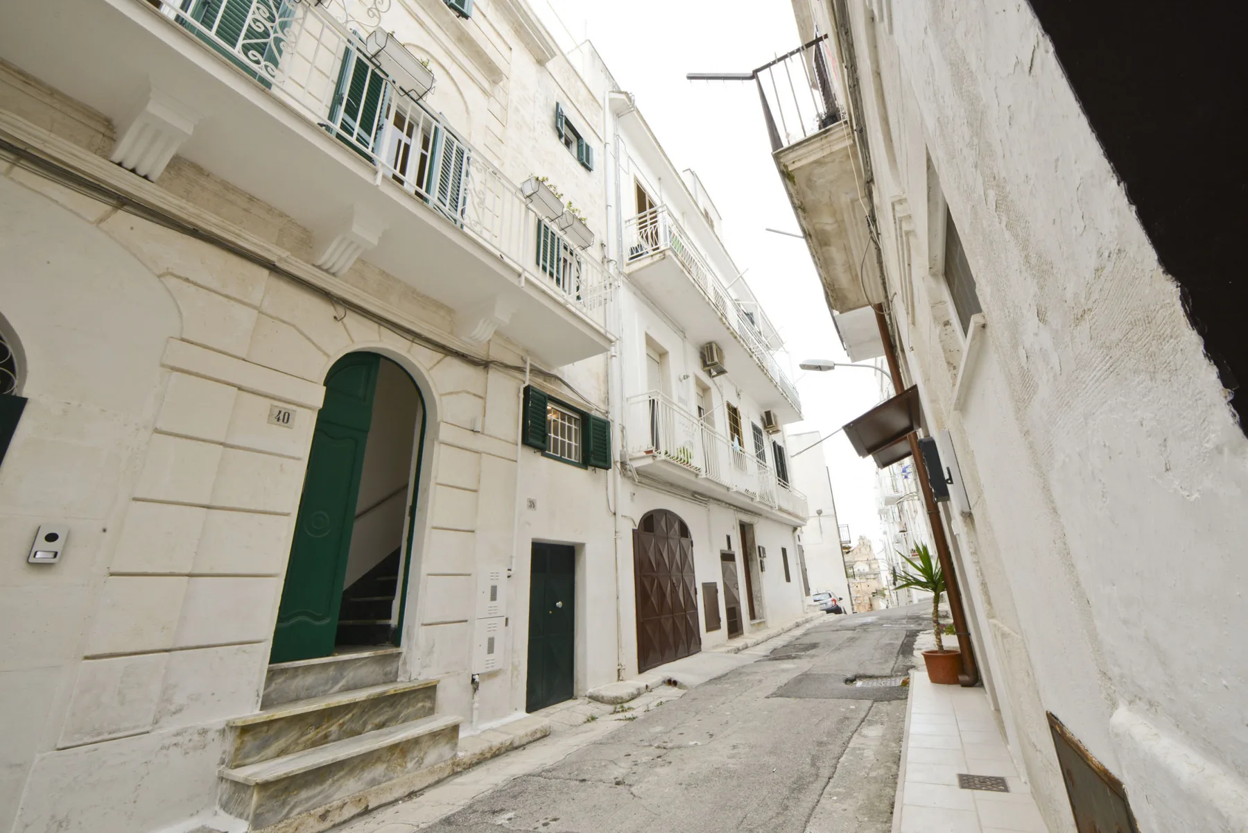 Una calle estrecha pasa entre edificios blancos con balcones y puertas arqueadas.