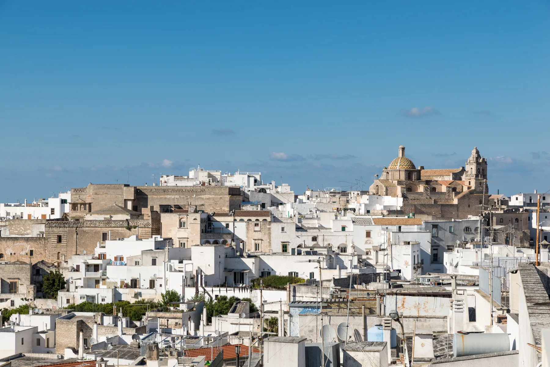Un paisaje urbano de edificios blancos y de piedra se extiende bajo un cielo azul despejado.