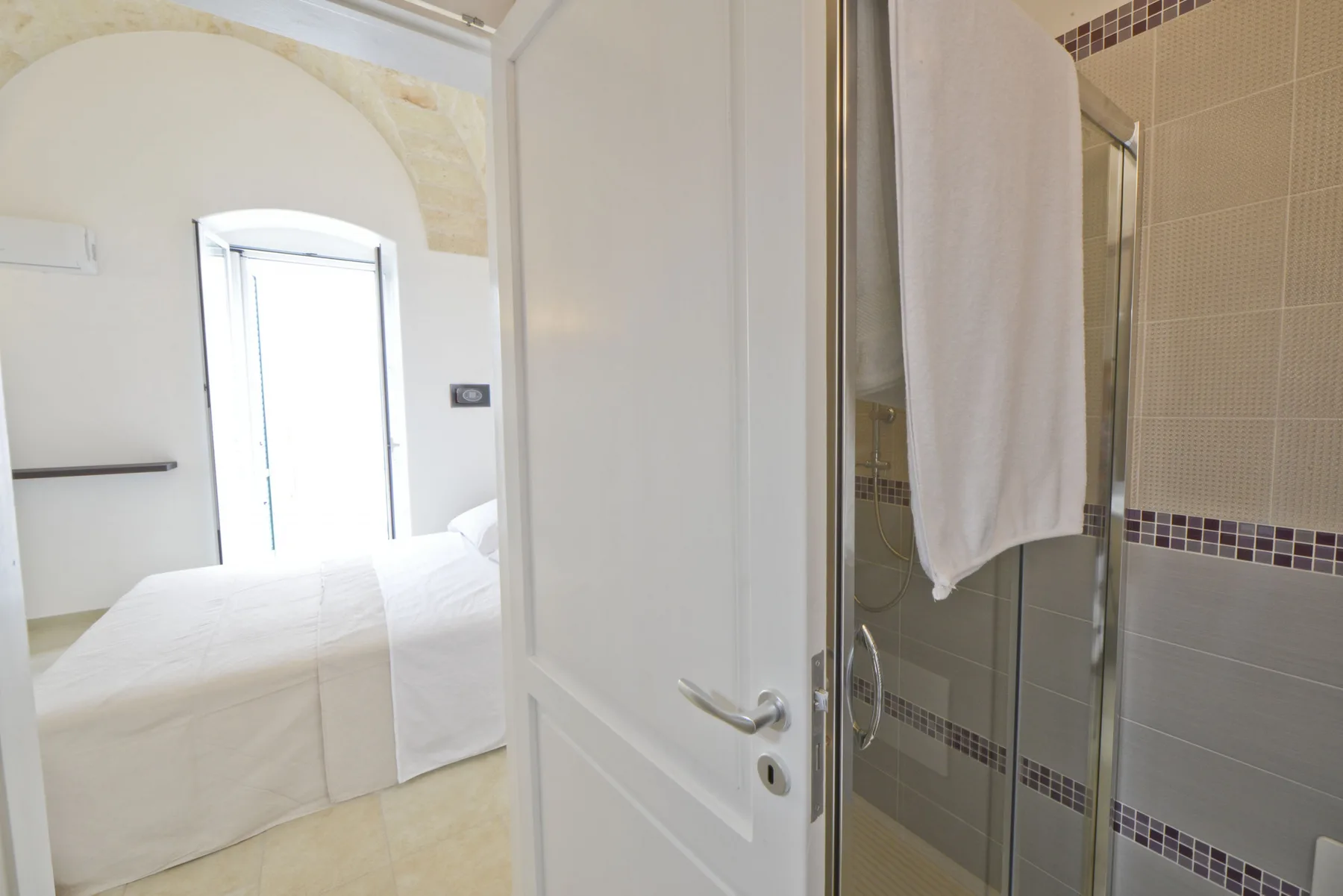 Un dormitorio con una cama junto a la ducha del baño.