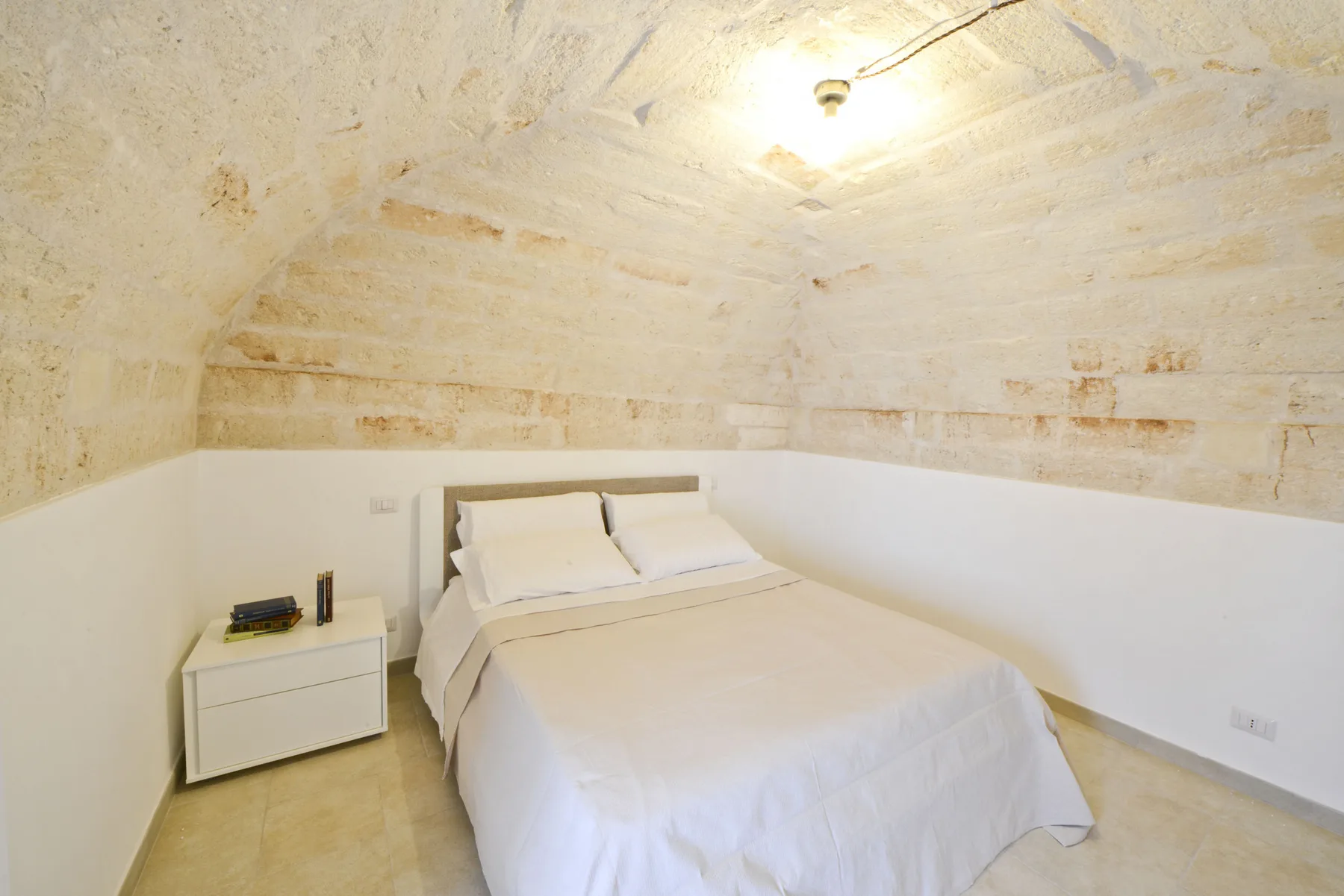 Dormitorio con una cama bajo un techo de piedra inclinado.