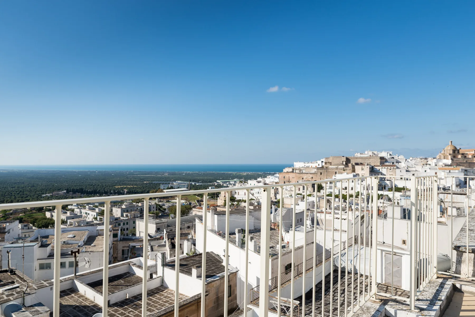 Una terraza en la azotea domina edificios blancos y una costa distante.