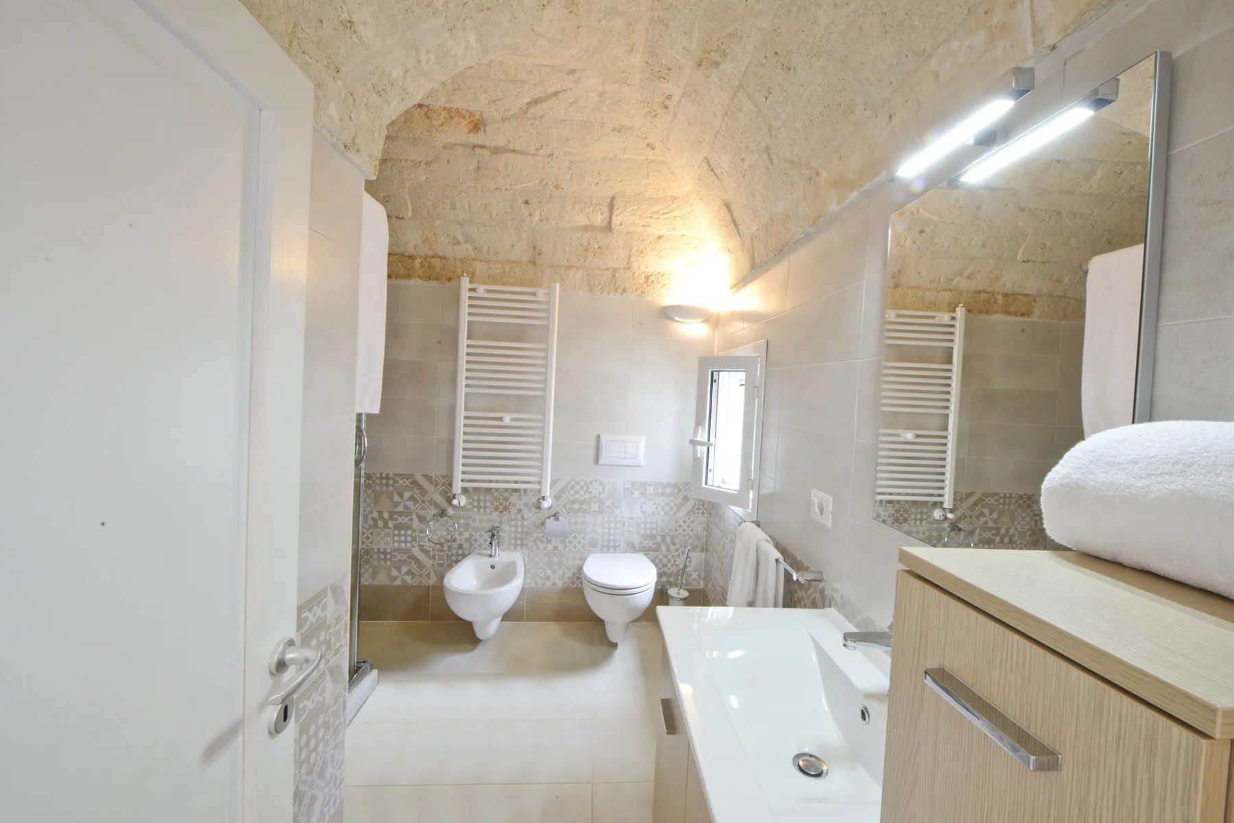 Un baño luminoso con bañera, inodoro y lavabo de pared.