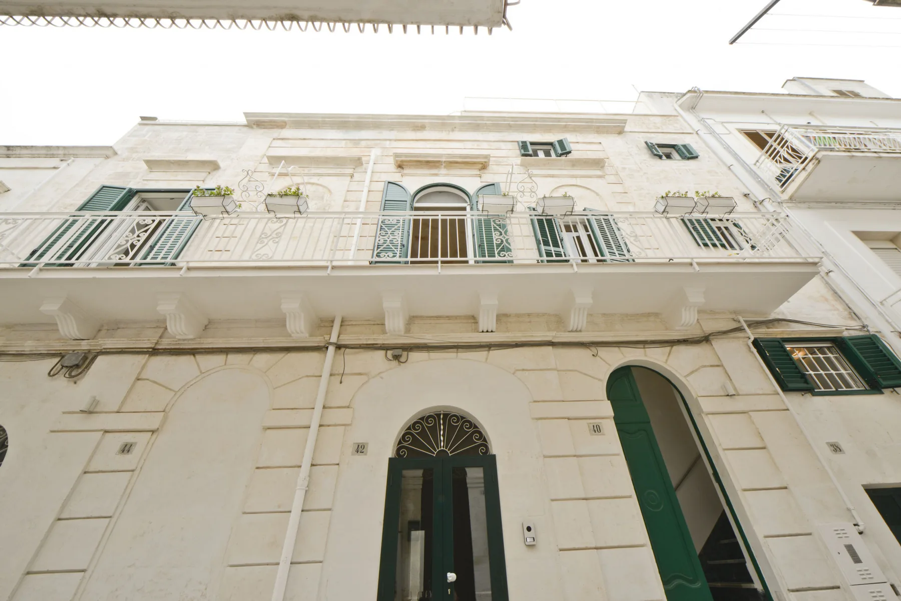 Una fachada de piedra clara con balcones y puertas arqueadas.