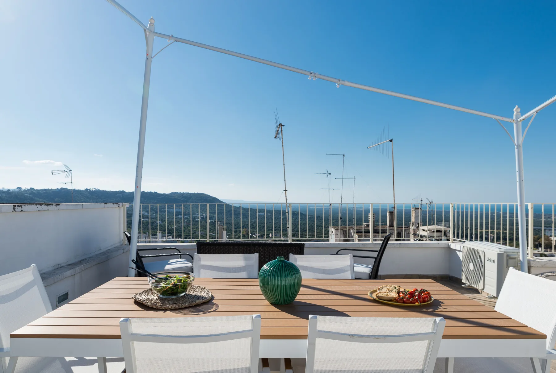 A rooftop terrace dining area with a table overlooking the sea.