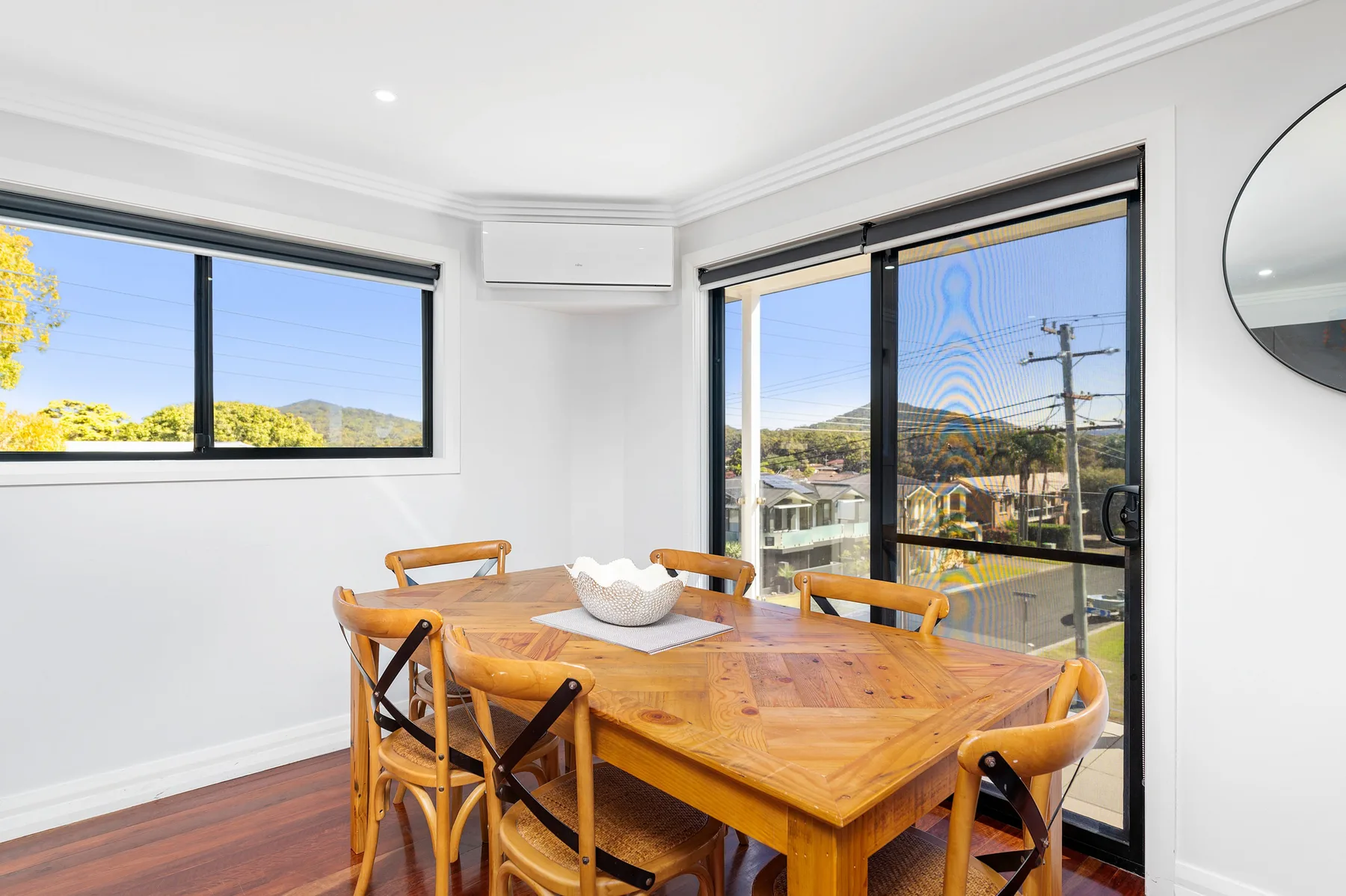 Comedor con mesa de madera y grandes ventanas con vistas al vecindario.