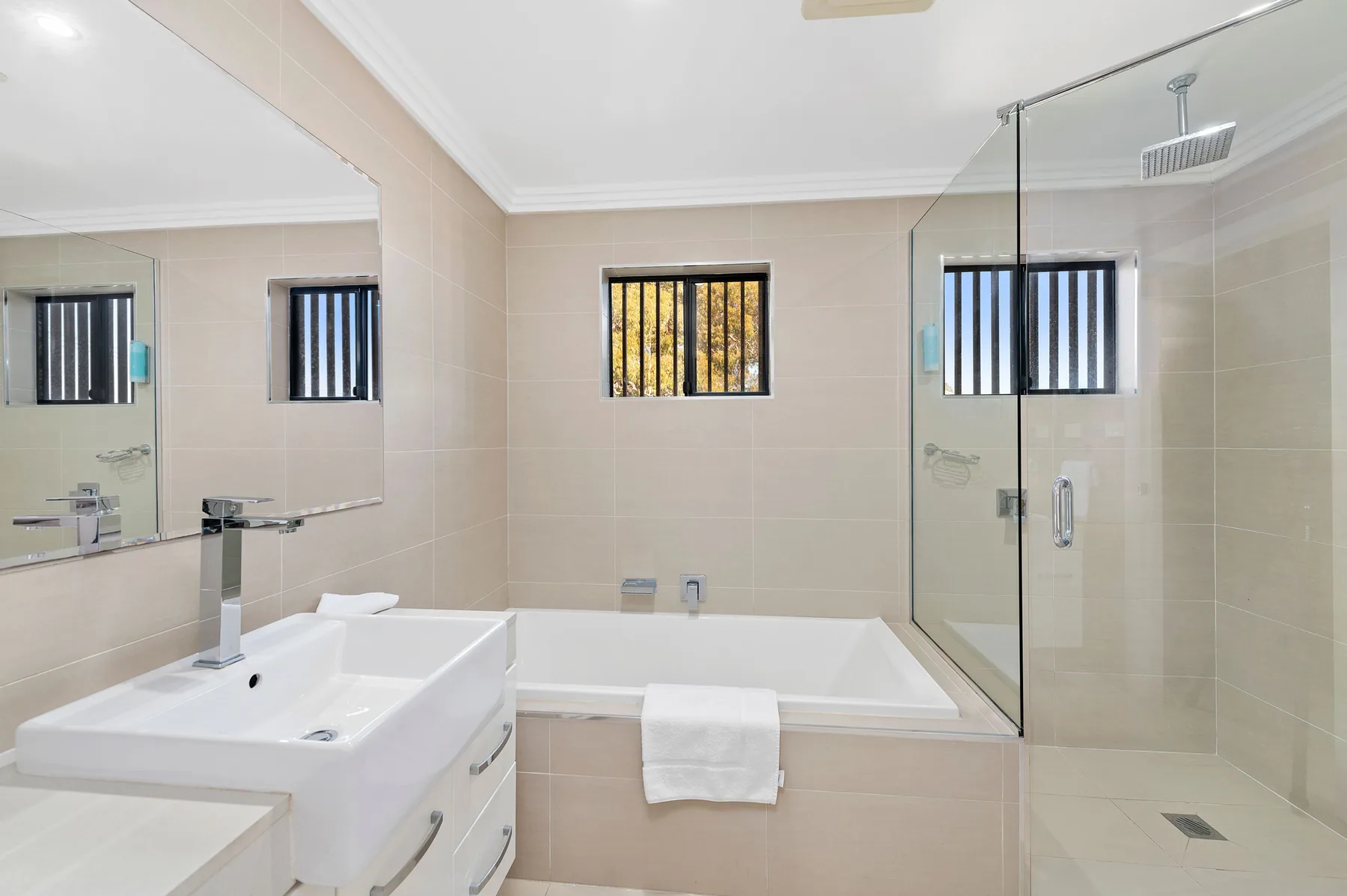 Un baño revestido de azulejos con bañera, lavabo y ducha de cristal.