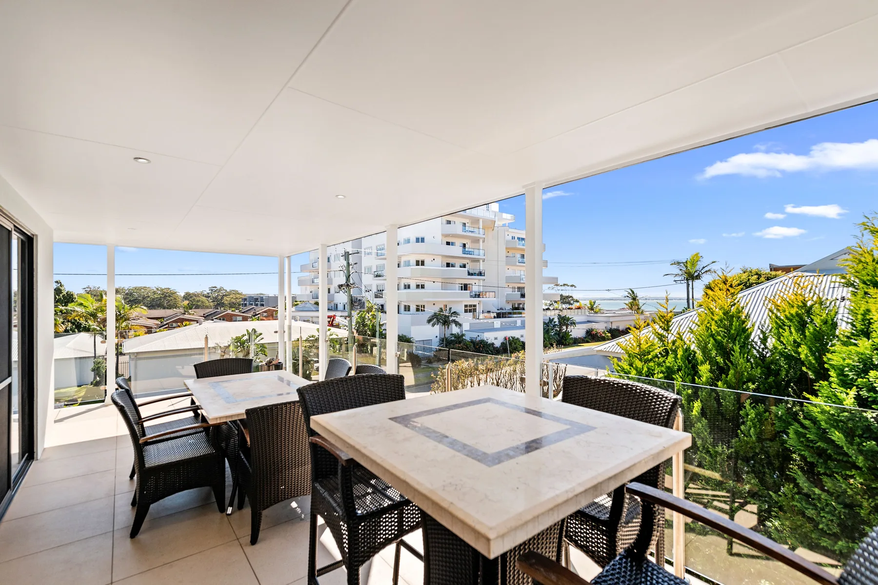 A covered outdoor dining area with tables, seating, and views of nearby buildings.