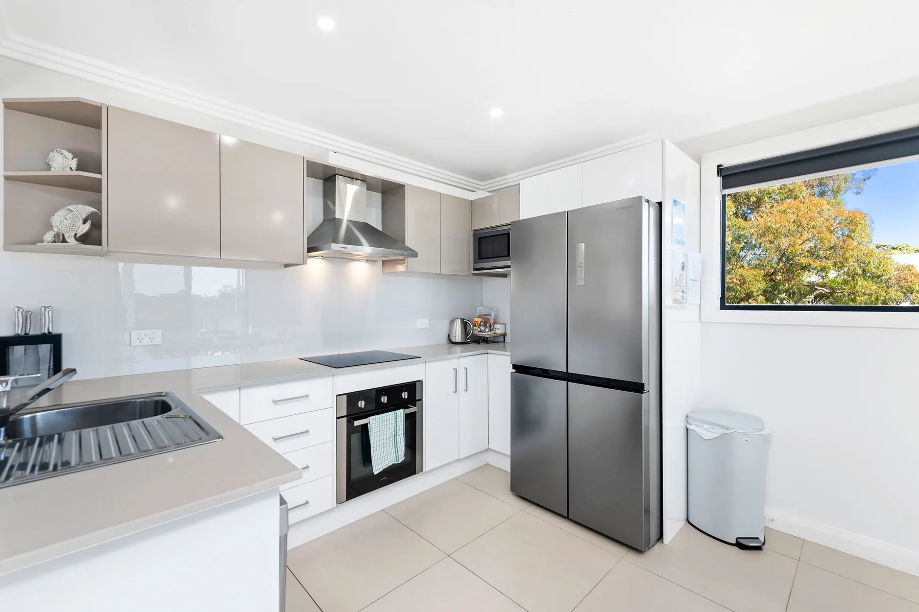 Una cocina moderna y luminosa con gabinetes blancos, electrodomésticos de acero inoxidable y una ventana.