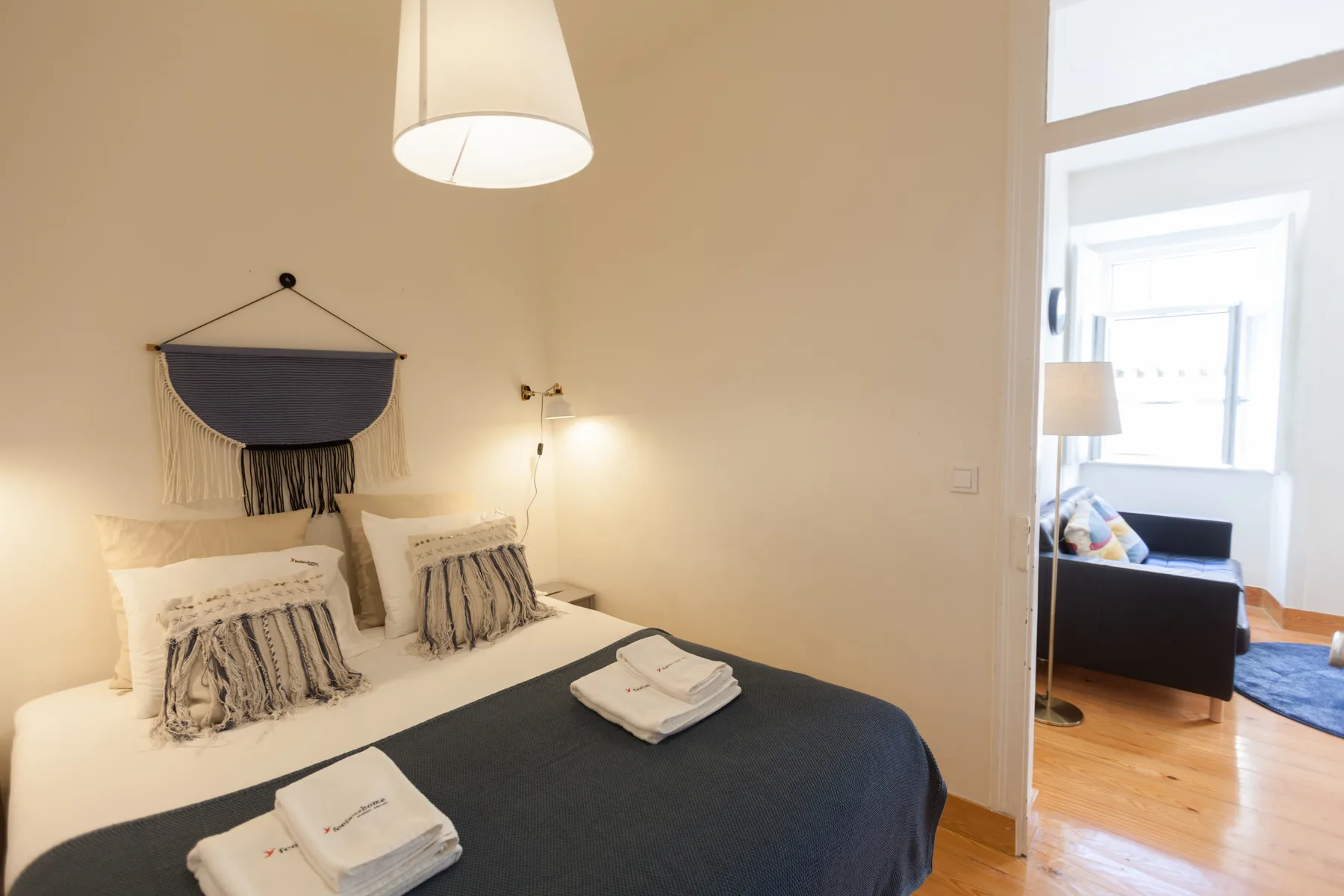 Un dormitorio con una cama doble y vistas a una estancia contigua luminosa.