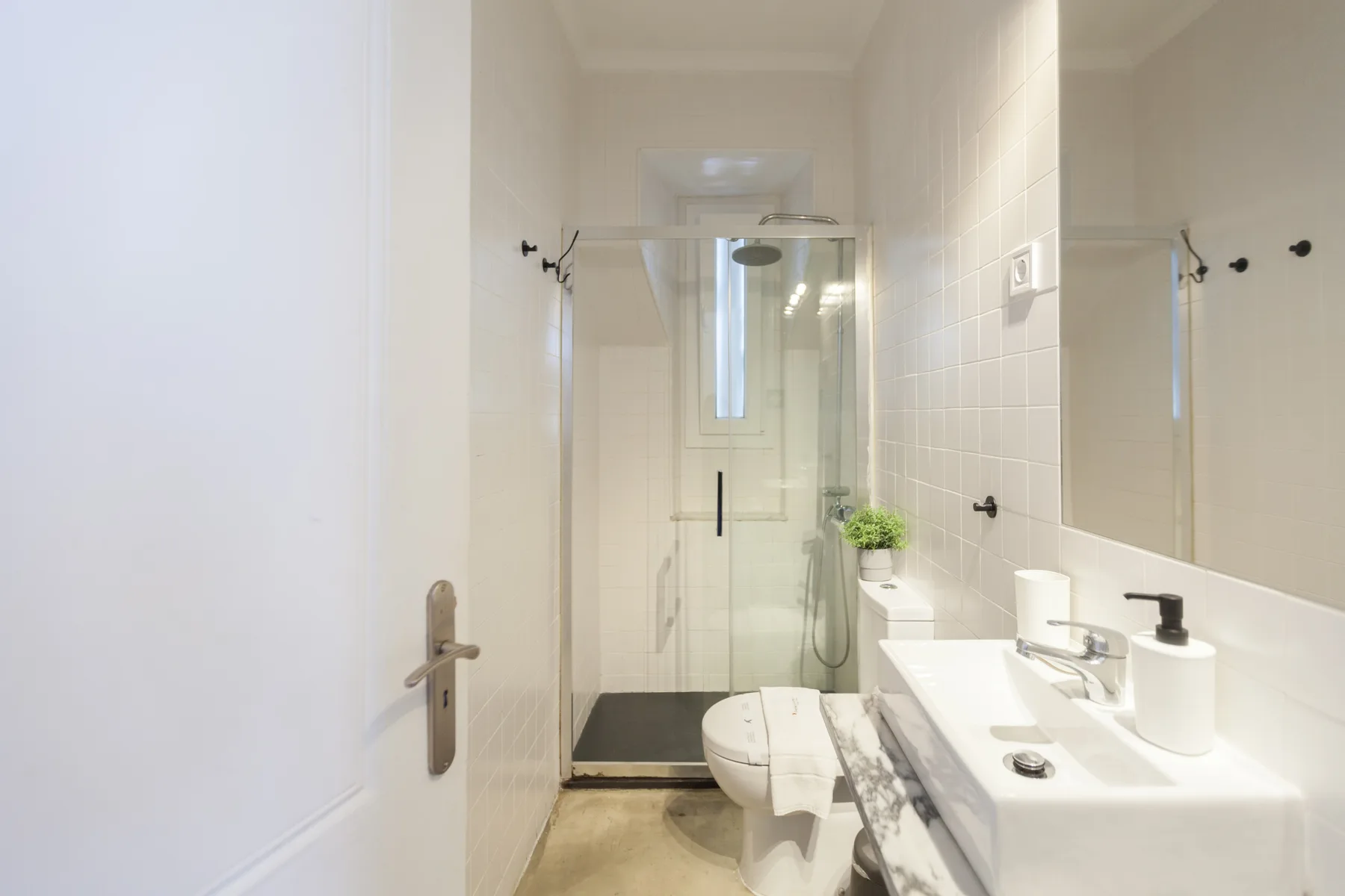Un baño luminoso con ducha de cristal, inodoro y lavabo.