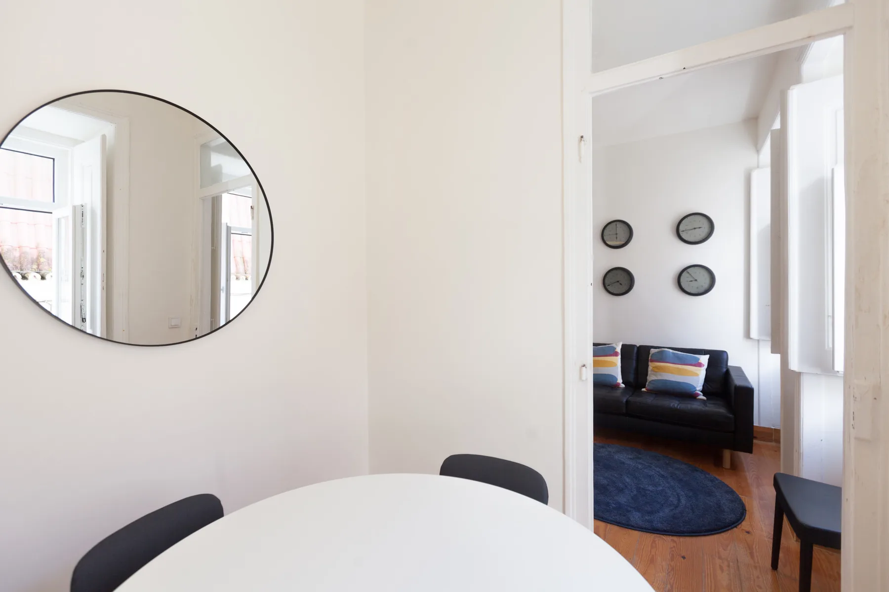 A dining area with a white table and a view into a living room.