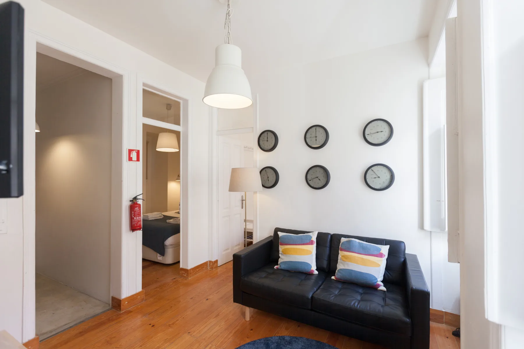 Living room with a black sofa and several clocks on the wall.