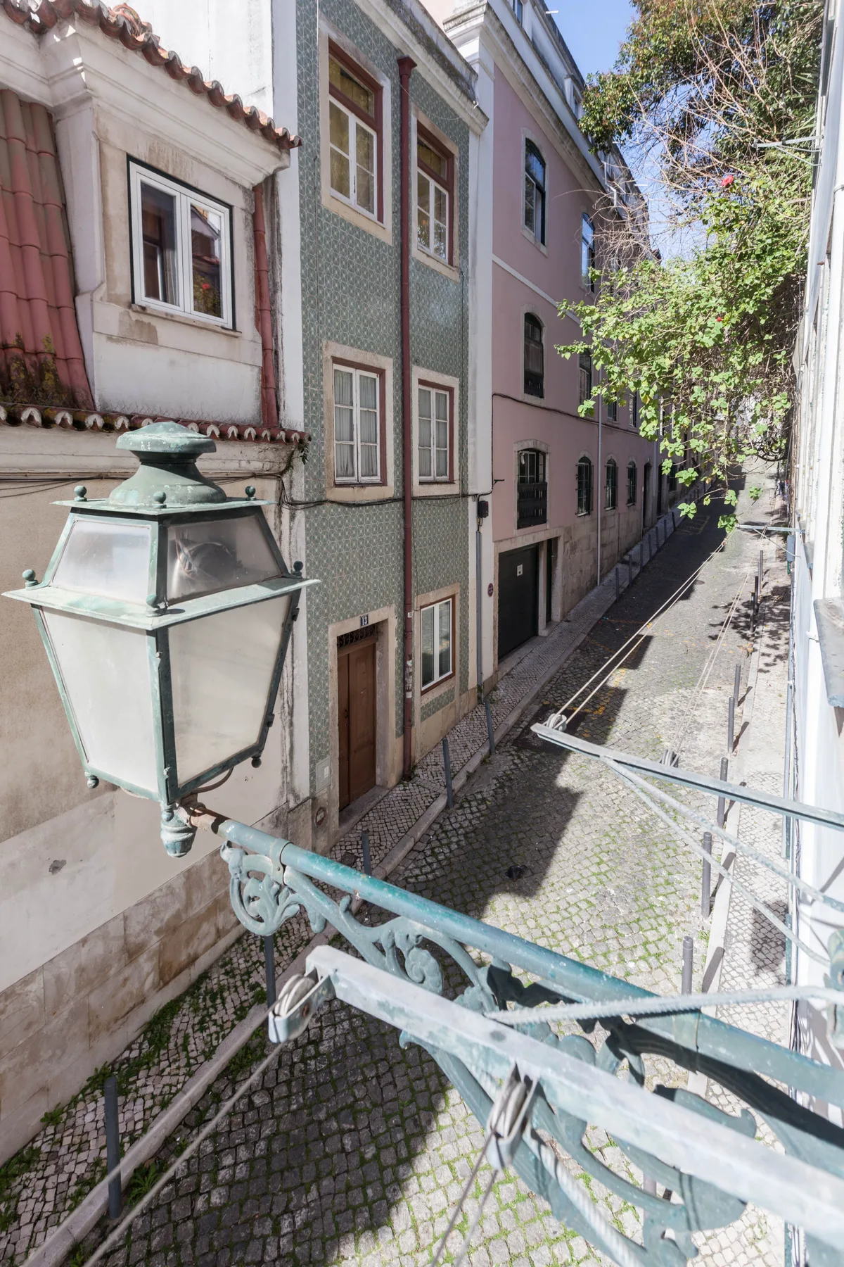 Una calle empedrada pasa entre edificios de colores, con una farola decorativa en primer plano.