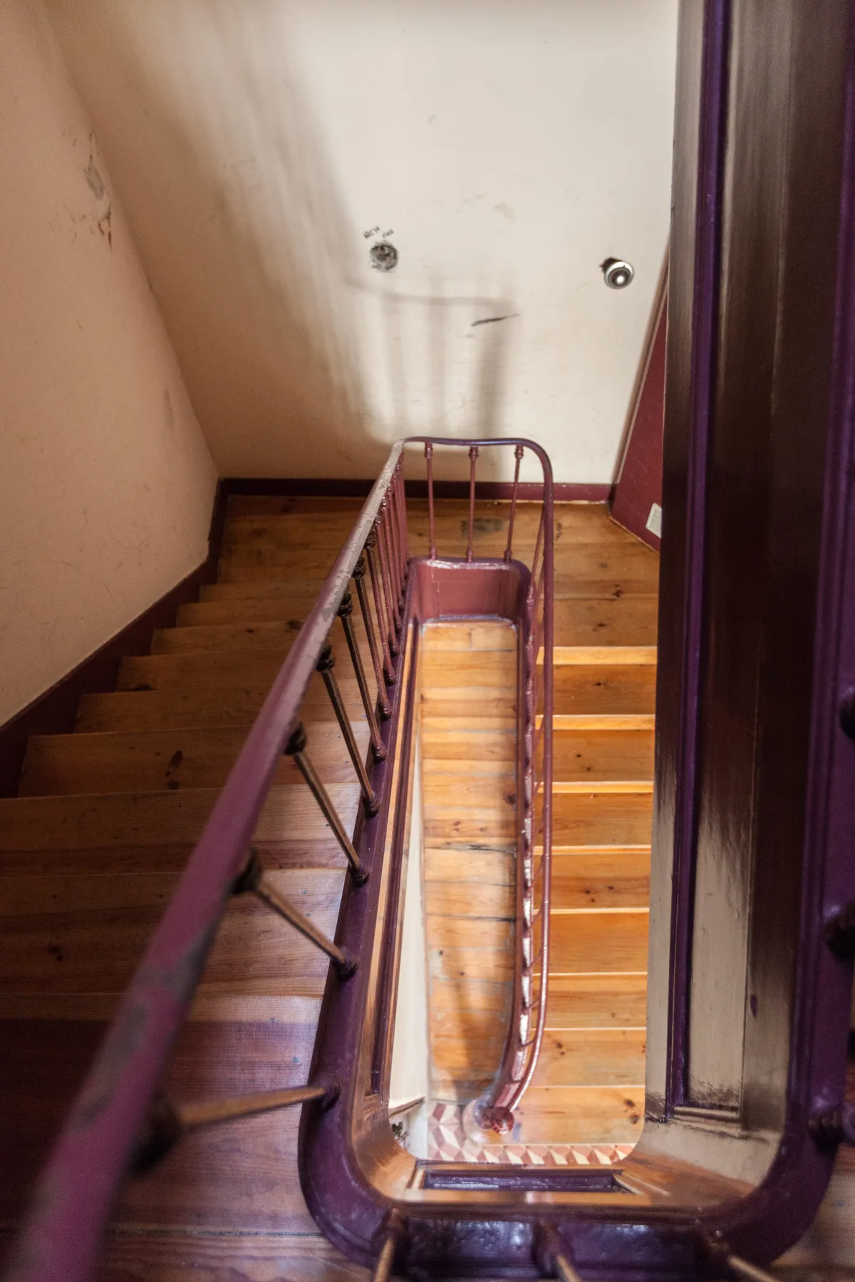 Escalera interior con peldaños de madera y una barandilla central.