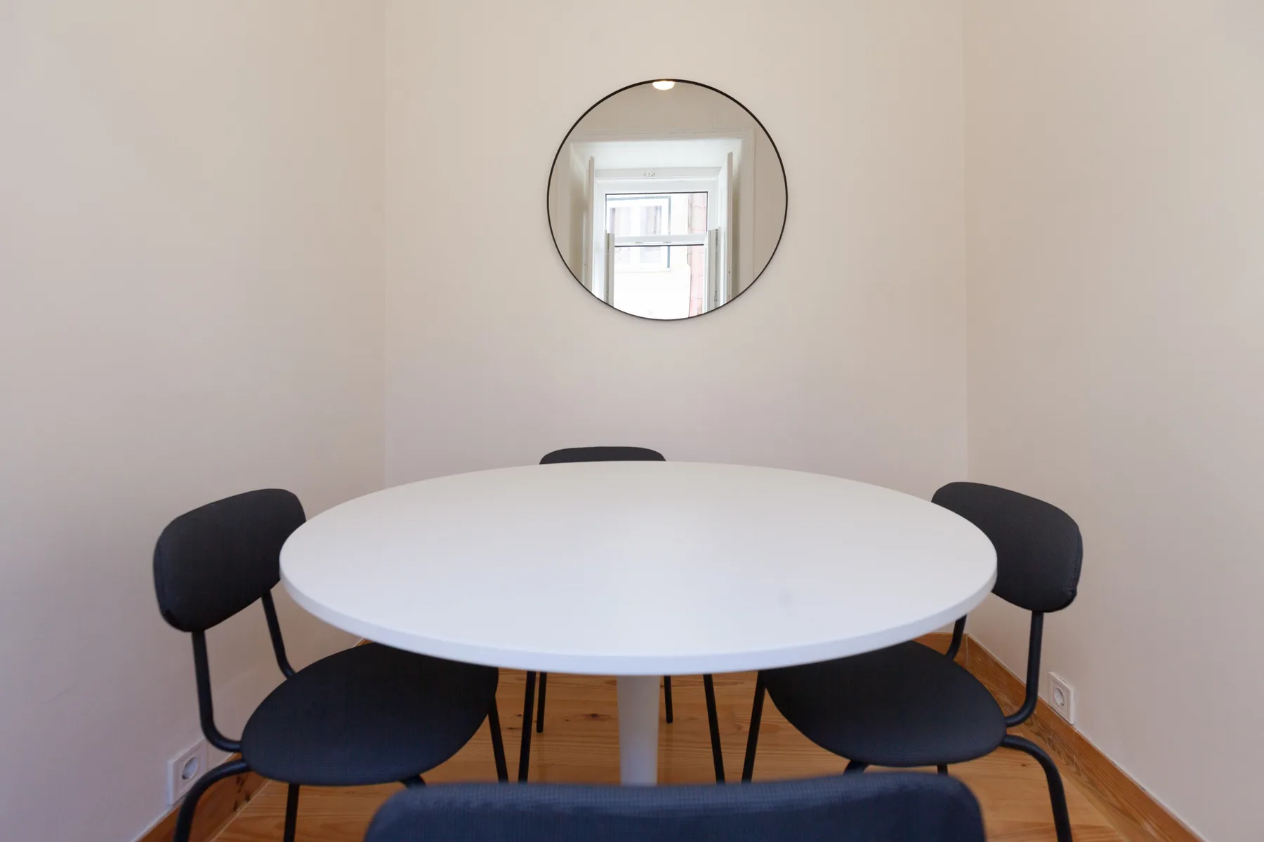 A small dining area with a round table and dark seating.