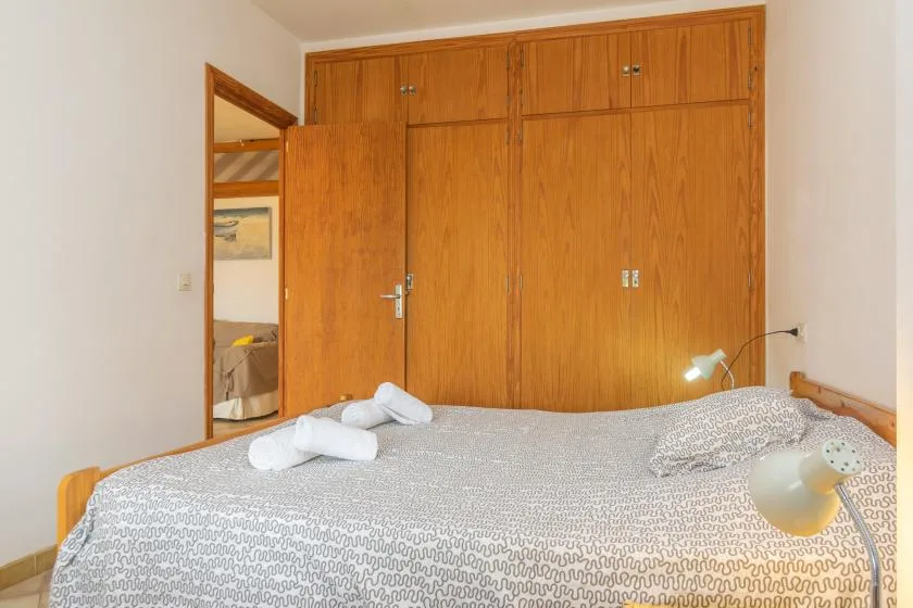 Un dormitorio con una cama cubierta con ropa estampada y armarios de madera.