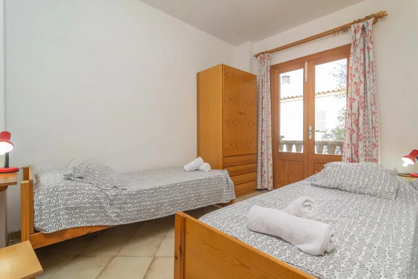 Un dormitorio con dos camas, un armario de madera y una puerta acristalada.
