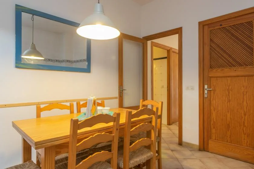 Comedor con una mesa y sillas de madera bajo una lámpara colgante.
