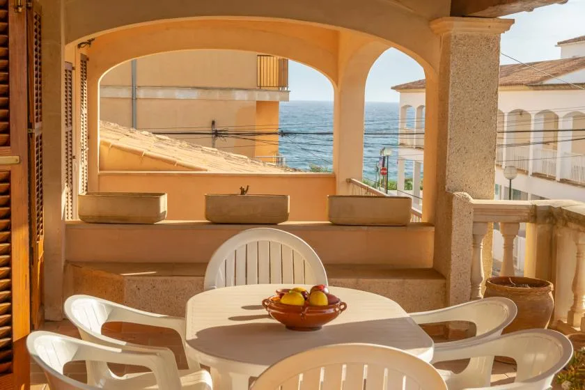 A covered terrace with a dining table and views of the sea.